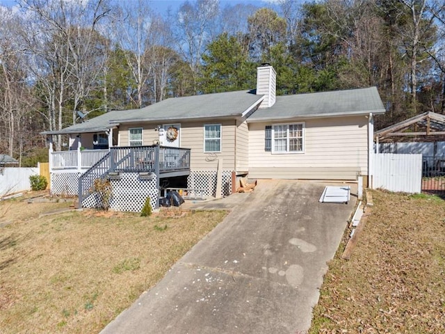 ranch-style house with a front lawn, a chimney, fence, and a wooden deck