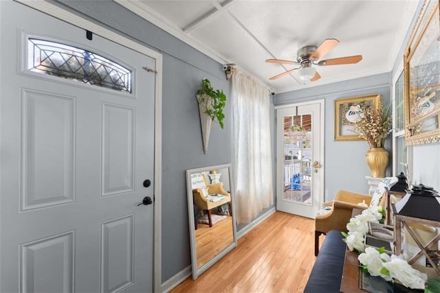 doorway featuring ceiling fan, ornamental molding, light wood-style flooring, and baseboards