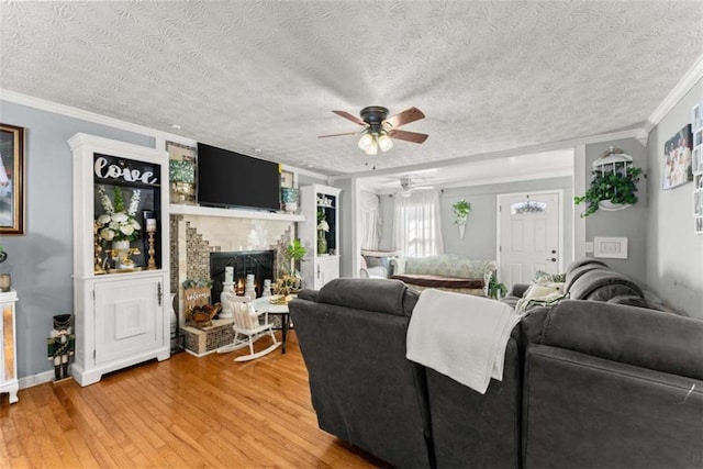 living room with a large fireplace, crown molding, a textured ceiling, and wood finished floors