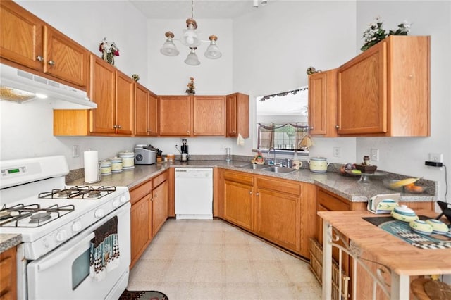 kitchen with white appliances, a sink, under cabinet range hood, a high ceiling, and light flooring