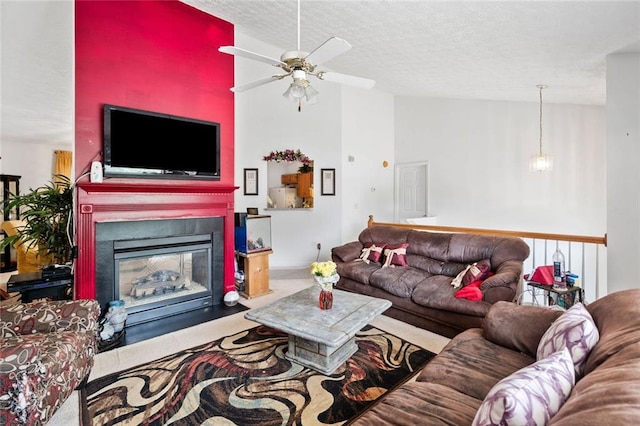 living room featuring ceiling fan, a textured ceiling, a fireplace with flush hearth, and high vaulted ceiling