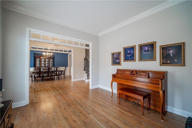 living area featuring a chandelier, crown molding, wood finished floors, baseboards, and stairs