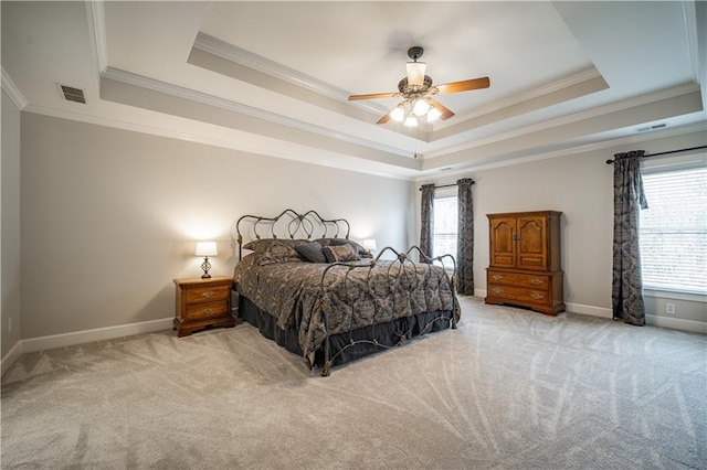 carpeted bedroom featuring a raised ceiling, crown molding, baseboards, and a ceiling fan
