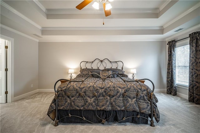 carpeted bedroom featuring ornamental molding, a tray ceiling, baseboards, and ceiling fan