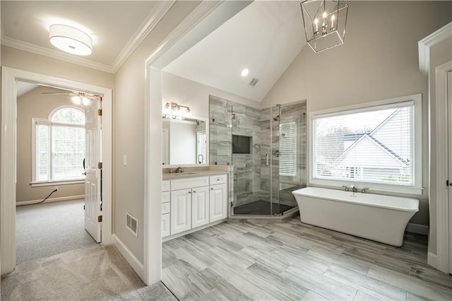 bathroom featuring vanity, lofted ceiling, a shower stall, ornamental molding, and a freestanding tub