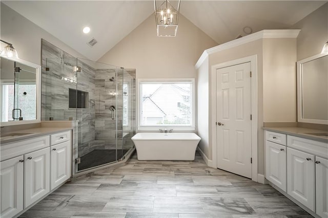 bathroom with two vanities, a stall shower, a freestanding bath, high vaulted ceiling, and recessed lighting