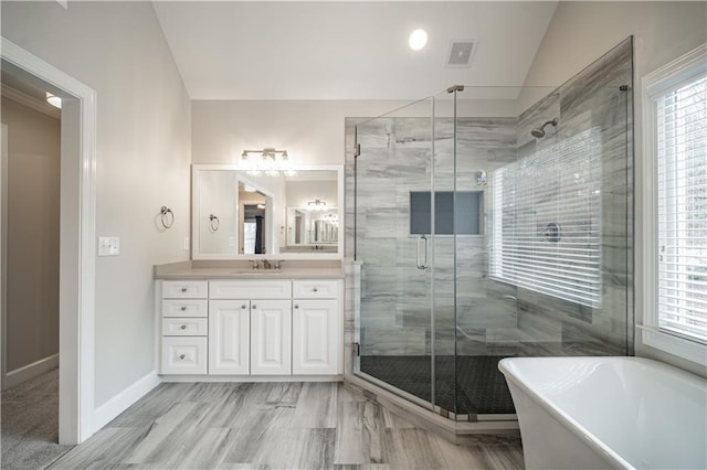 full bath with vanity, a stall shower, a soaking tub, plenty of natural light, and vaulted ceiling