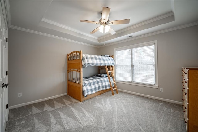 carpeted bedroom featuring a tray ceiling, crown molding, baseboards, and ceiling fan