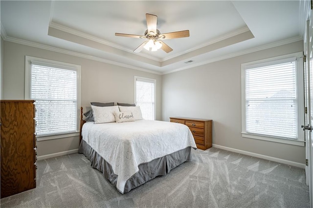 bedroom featuring a raised ceiling, light carpet, ornamental molding, baseboards, and a ceiling fan