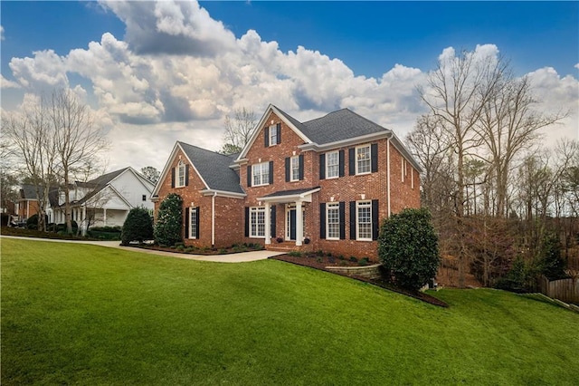 colonial-style house featuring brick siding and a front yard