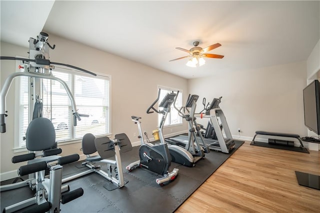 workout room featuring a ceiling fan, baseboards, and wood finished floors