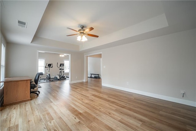 office area with a raised ceiling, a ceiling fan, light wood-style floors, and baseboards