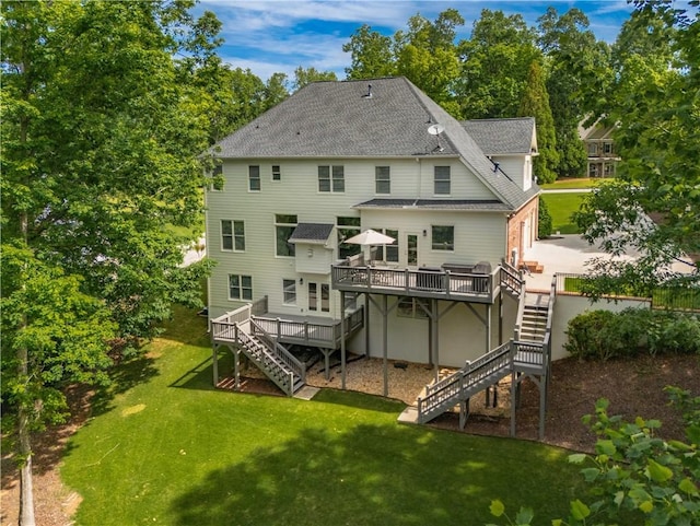 rear view of property featuring stairway, a wooden deck, roof with shingles, and a lawn