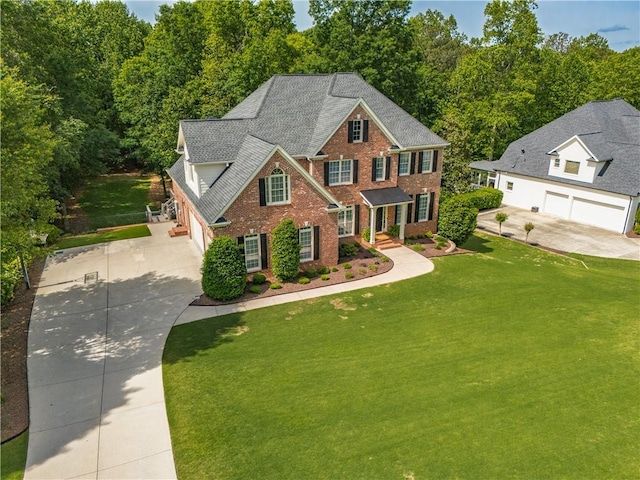 view of front of property with driveway, brick siding, a front yard, and a garage