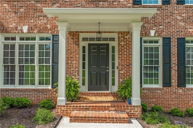view of exterior entry featuring brick siding