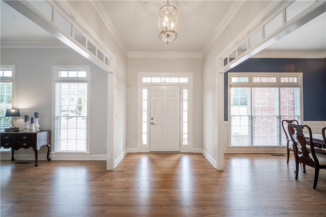 entrance foyer featuring wood finished floors, a chandelier, crown molding, and baseboards