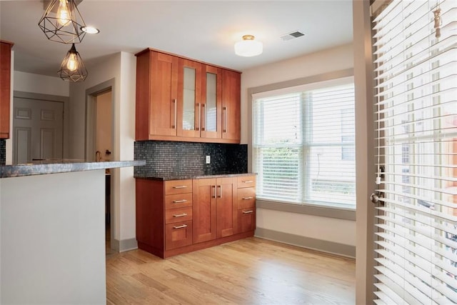 3050 Baymount Dr, Lawrenceville, GA 30043 - kitchen featuring light wood finished floors, brown cabinets, decorative backsplash, glass insert cabinets, and hanging light fixtures