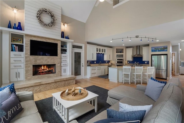 living room with light wood-type flooring, high vaulted ceiling, and a fireplace