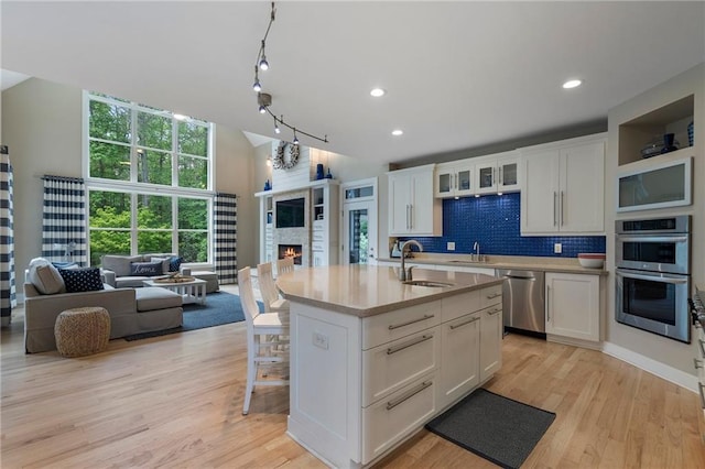 kitchen with a sink, white cabinetry, appliances with stainless steel finishes, and open floor plan