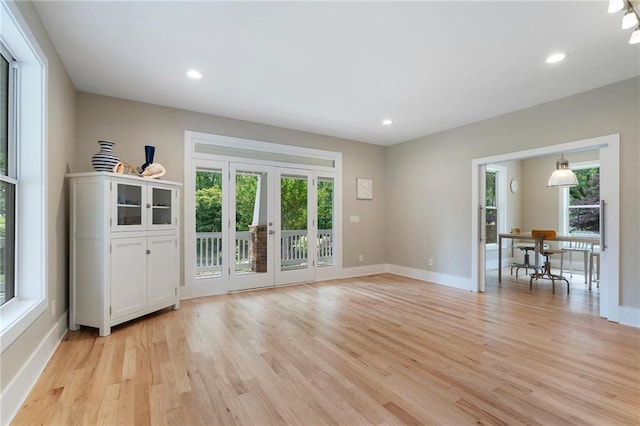 unfurnished living room featuring baseboards, french doors, light wood-style flooring, and recessed lighting