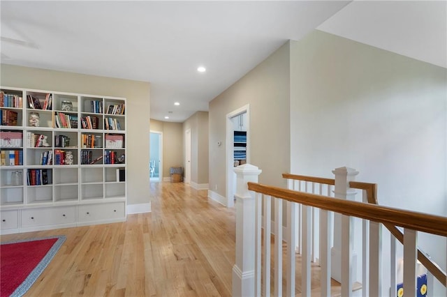 hallway featuring recessed lighting, baseboards, wood finished floors, and an upstairs landing
