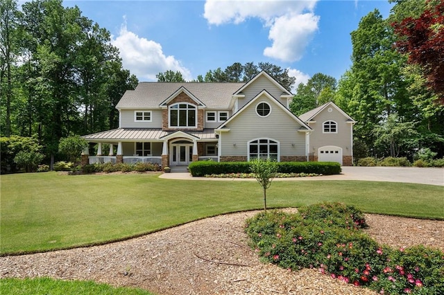 craftsman house featuring covered porch, concrete driveway, french doors, and a front yard