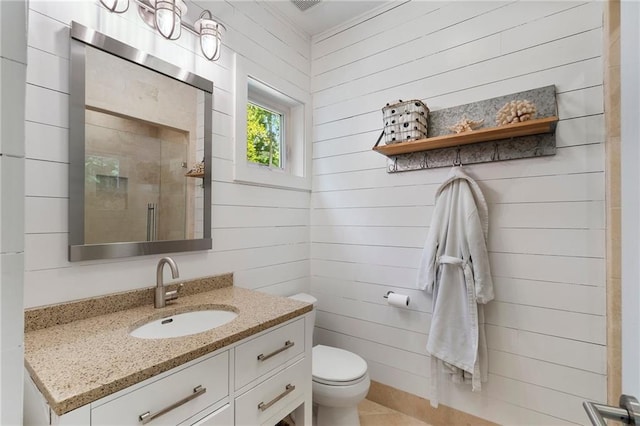 full bath with vanity, wood walls, a tile shower, and toilet