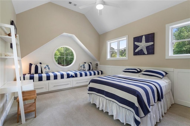 bedroom featuring light colored carpet, lofted ceiling, a wainscoted wall, and visible vents