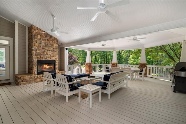 wooden deck with outdoor dining area, a ceiling fan, an outdoor living space with a fireplace, and a grill