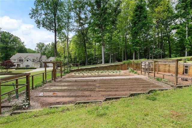view of home's community featuring fence, a lawn, and a vegetable garden