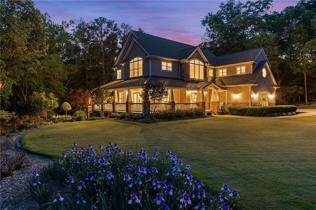 view of front of property featuring a lawn, covered porch, metal roof, and a standing seam roof