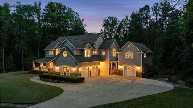 view of front of house featuring a garage, concrete driveway, stone siding, a porch, and a front lawn