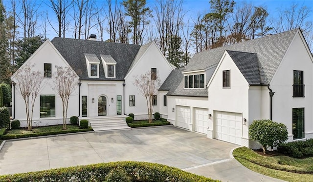 view of front facade with an attached garage, a shingled roof, driveway, stucco siding, and a chimney