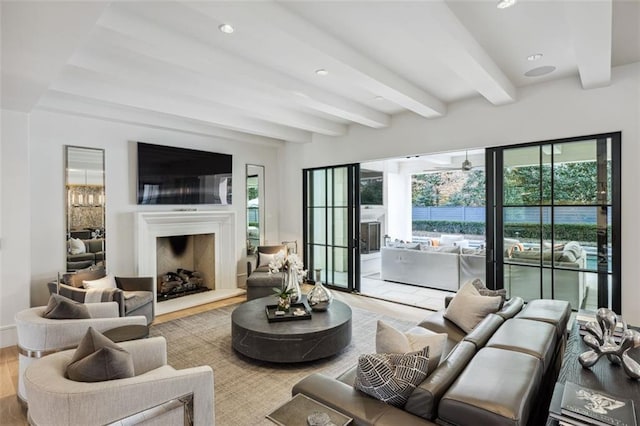 living room featuring beam ceiling, a fireplace with raised hearth, wood finished floors, and recessed lighting