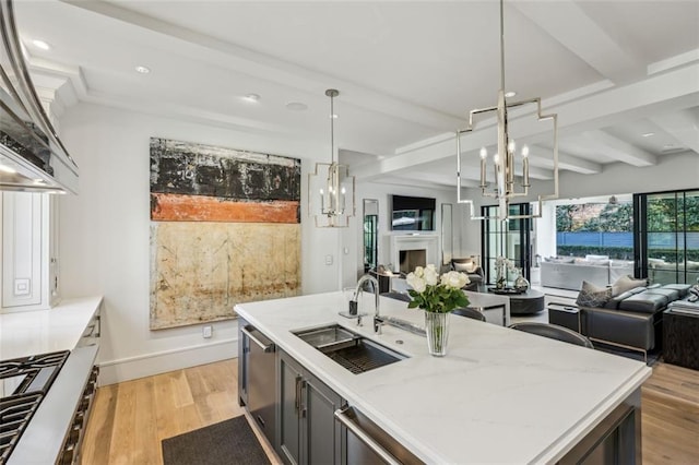 kitchen featuring open floor plan, beamed ceiling, a fireplace, and a sink