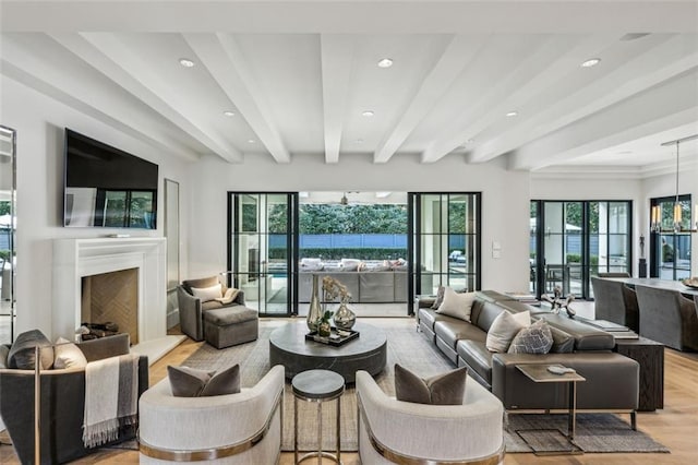 living room featuring recessed lighting, a fireplace with raised hearth, light wood-style floors, a chandelier, and beamed ceiling