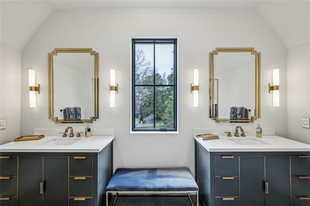 full bath featuring lofted ceiling, two vanities, and a sink