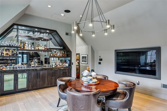 dining room with lofted ceiling, bar, visible vents, and wood finished floors