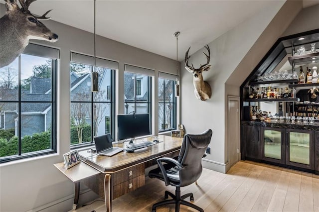 office area with a dry bar, baseboards, and wood finished floors