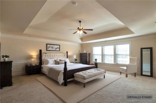 carpeted bedroom featuring a raised ceiling, ceiling fan, and crown molding