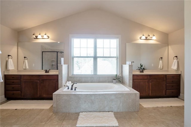 bathroom featuring lofted ceiling, a sink, a stall shower, two vanities, and a garden tub