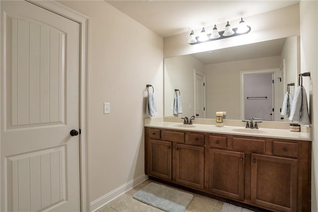 bathroom featuring baseboards, tile patterned flooring, double vanity, and a sink
