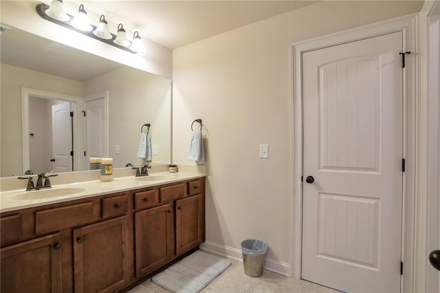 full bathroom featuring double vanity, baseboards, tile patterned flooring, and a sink