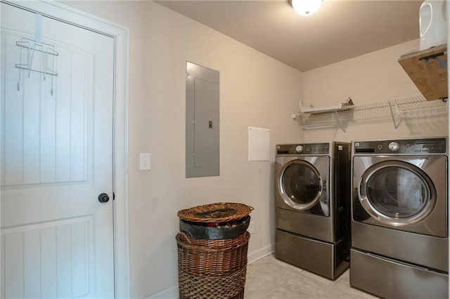 clothes washing area featuring laundry area, washing machine and clothes dryer, electric panel, baseboards, and light tile patterned flooring