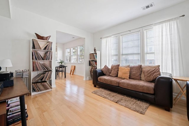 living area with light wood finished floors, visible vents, and baseboards