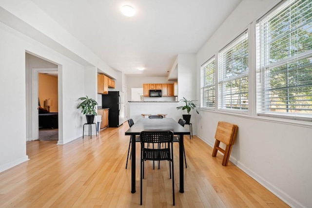 dining room with baseboards and light wood-type flooring