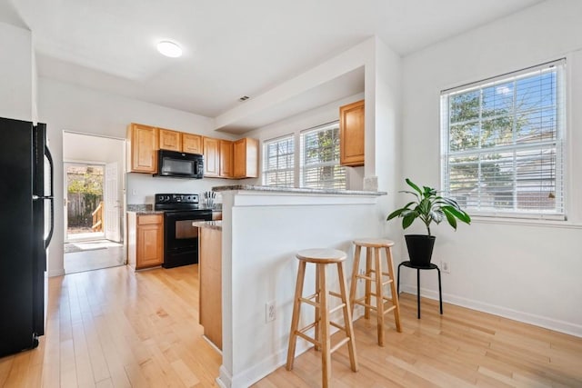 kitchen featuring plenty of natural light, light wood-style floors, and black appliances