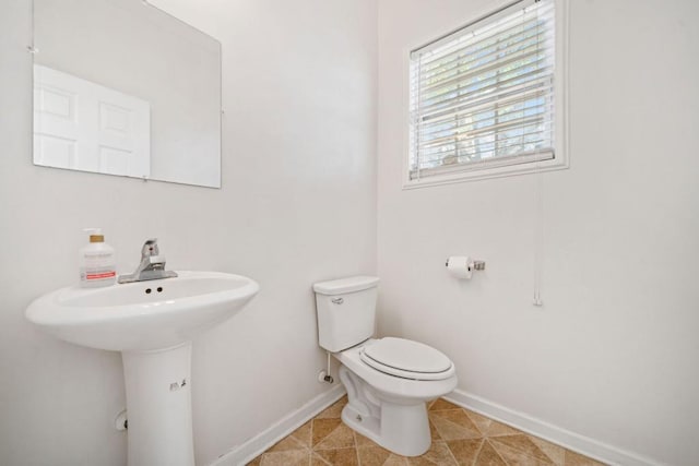 bathroom featuring tile patterned flooring, toilet, and baseboards