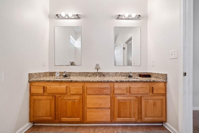 full bathroom with double vanity, baseboards, tile patterned floors, and a sink