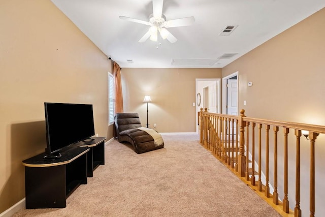 sitting room with attic access, light colored carpet, visible vents, and baseboards